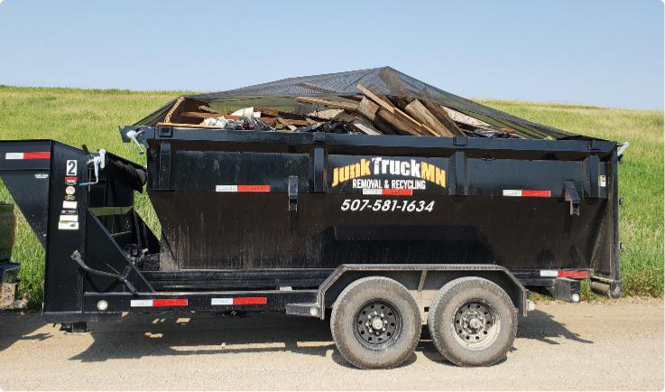 A large black Junk Truck MN commercial junk removal and recycling trailer filled with debris from a property cleanout in the South Metro area.