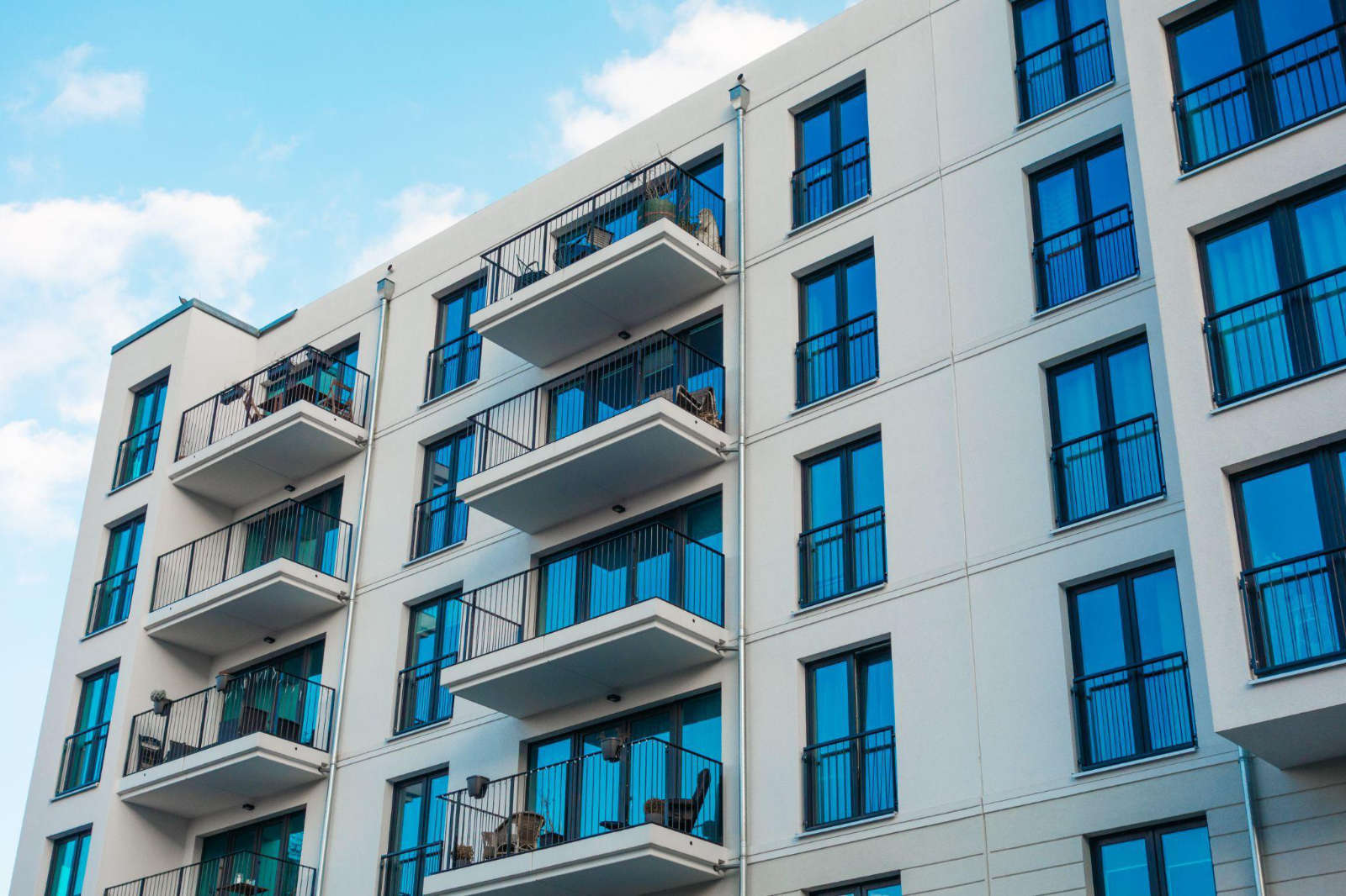 Exterior view of a modern multi-family apartment complex under a blue sky, representing residential properties that frequently require property management junk removal services.