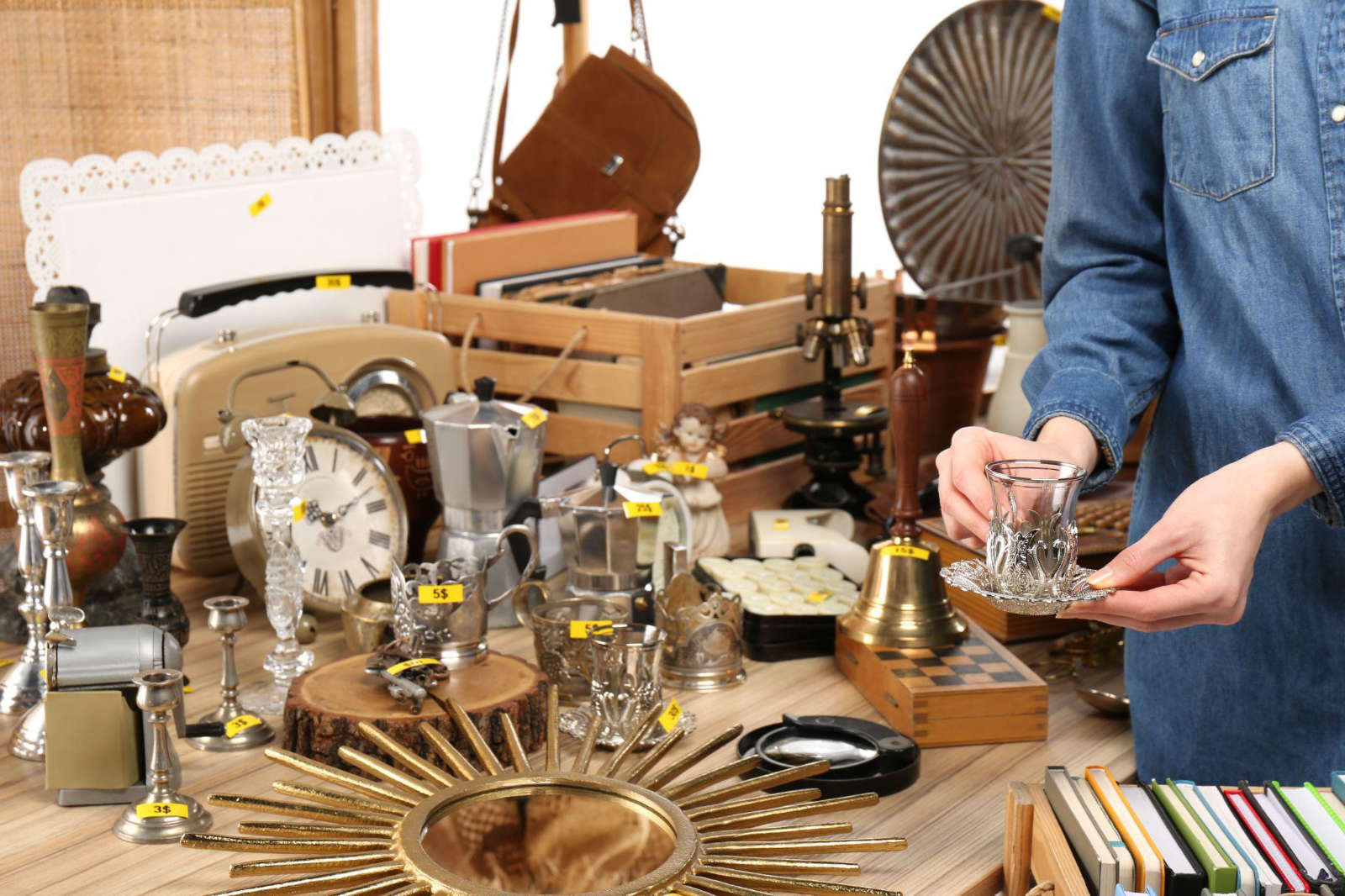A collection of priced vintage items, glassware, antiques, and decor displayed for an estate sale.