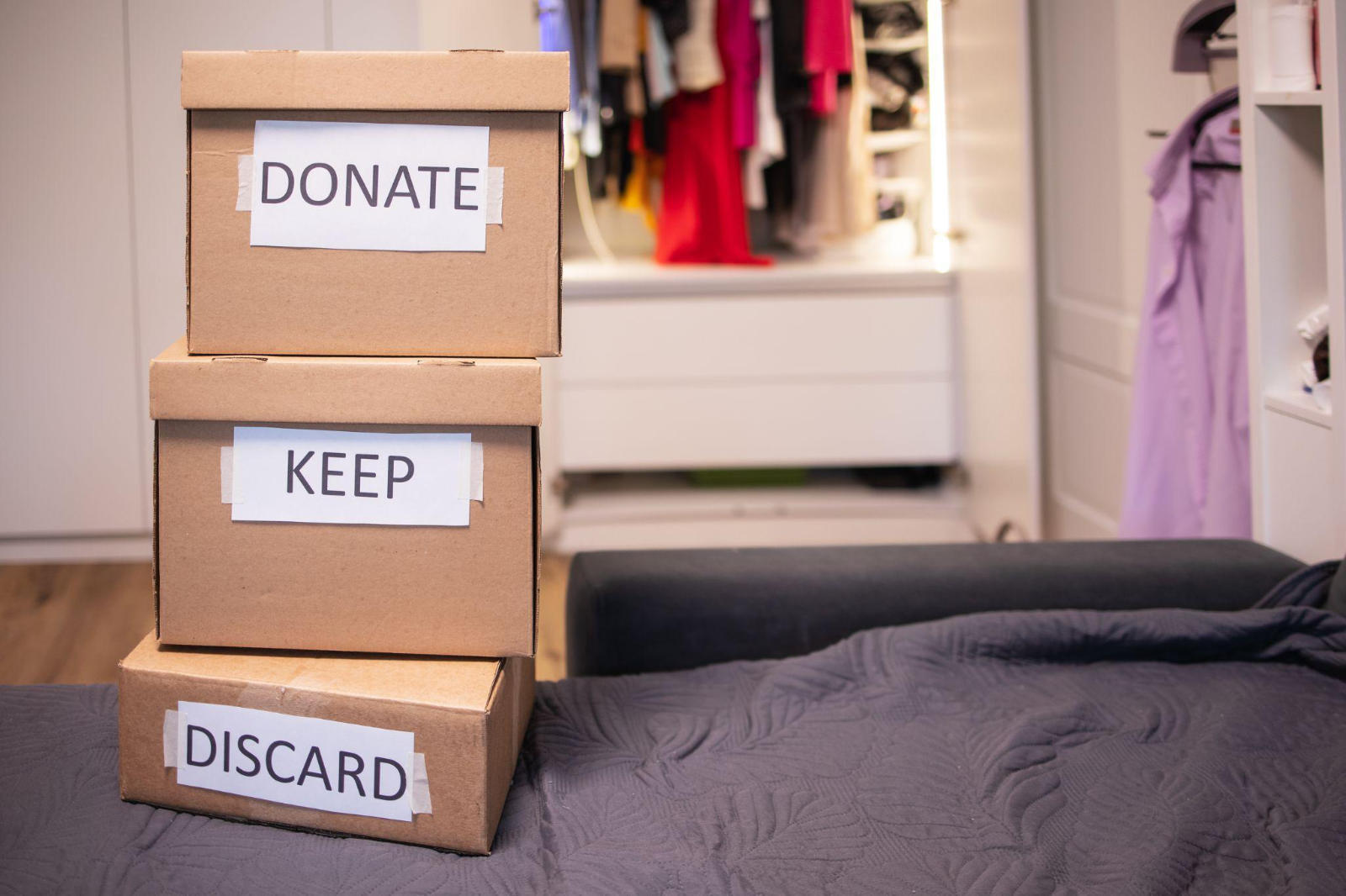 Three cardboard storage boxes stacked together labeled Donate, Keep, and Discard for a home cleanout.