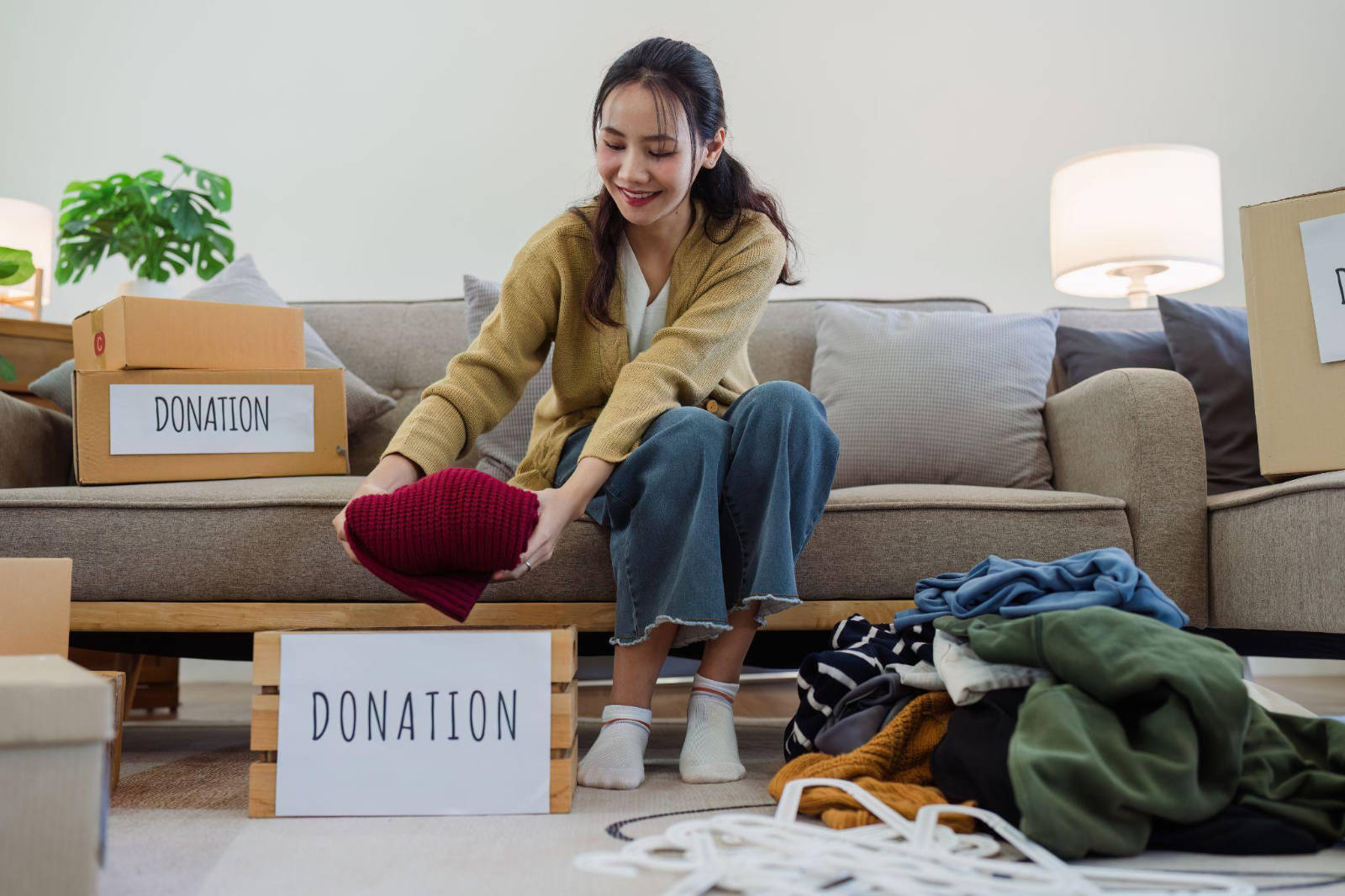 A woman sitting next to boxes labeled Donation while folding clothes to donate during an estate cleanout.