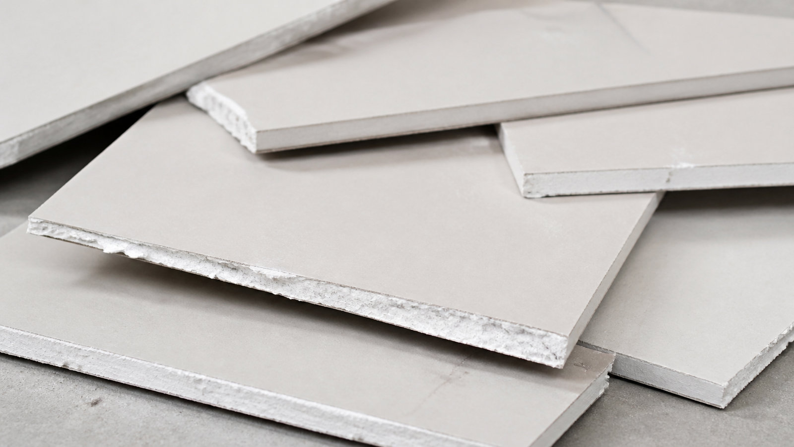 Stacked cut pieces of drywall sheets placed on the floor for disposal or recycling.