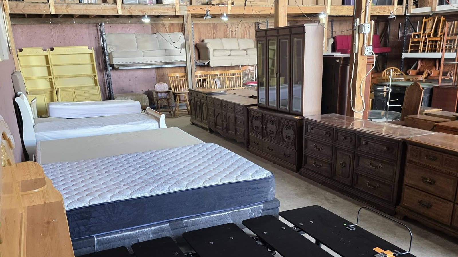 Warehouse filled with donated mattresses, dressers, wooden cabinets, and sofas ready for reuse.